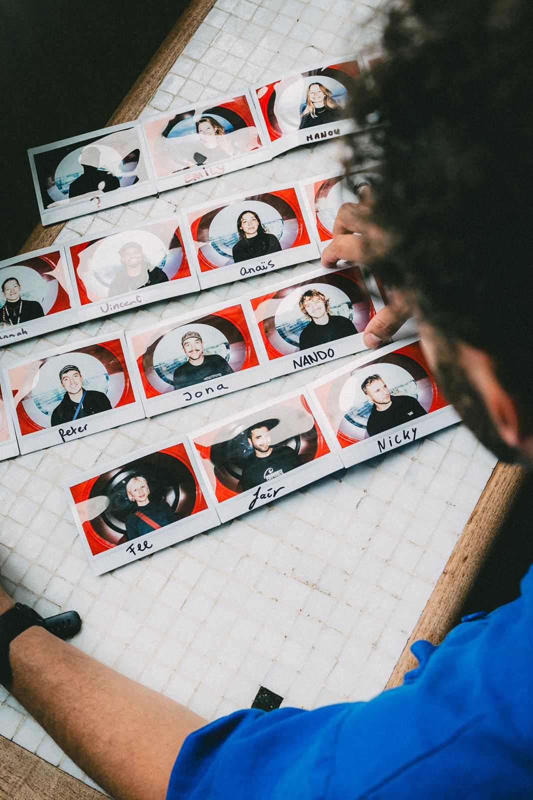 A photo of Dammes who is looking at polaroids. These polaroids are portraits of the peopel from his video crew.